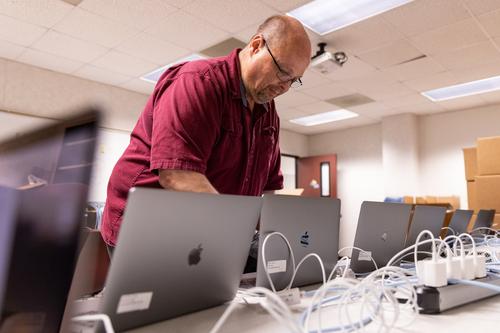A staff member sets up laptops